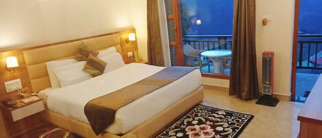 Habitación de hotel con una cama grande, lámparas de noche, una mesita y vistas al exterior.
