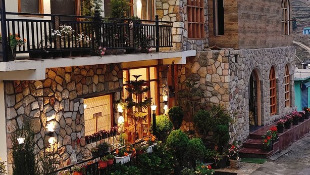 A two-story stone building with a balcony, potted plants, and a tiled pathway. - HOTEL ALPINE MUSK (Tehri)