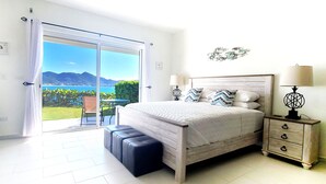 A bedroom with a large sliding glass door leading to a balcony with a scenic view.