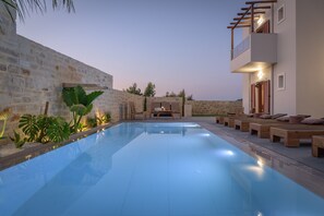 A swimming pool with lounge chairs and a stone wall.