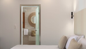 Ein Hotelzimmer mit einem Bett, einer Glastür zu einem Badezimmer, einem runden Spiegel und einer Wandleuchte.