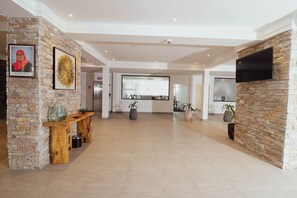 Welcome to our lobby, where guests can check in and unwind in a bright, airy space with a reception desk, flat-screen TV, and comfortable seating.
