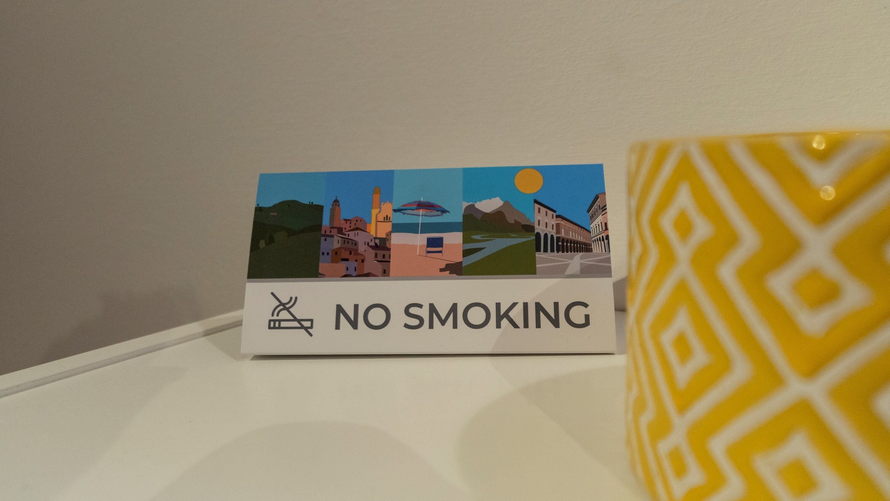 Ein 'RAUCHVERBOT'-Schild mit Illustrationen von Gebäuden und einer Sonne.