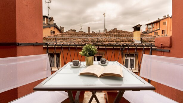 A balcony with a table, two cups, and an open book. - Italianway - Piella 5 (Bologna)