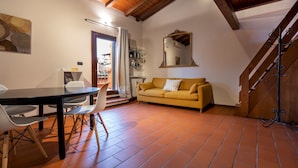 A cozy living room with a sofa, a dining table with chairs, and a staircase. - Italianway - Piella 5 (Bologna)