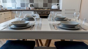 A modern kitchen with a dining table set for four, including bowls, glasses, and cutlery.
