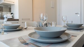 A dining table set with bowls, plates, glasses, and cutlery in a modern kitchen.
