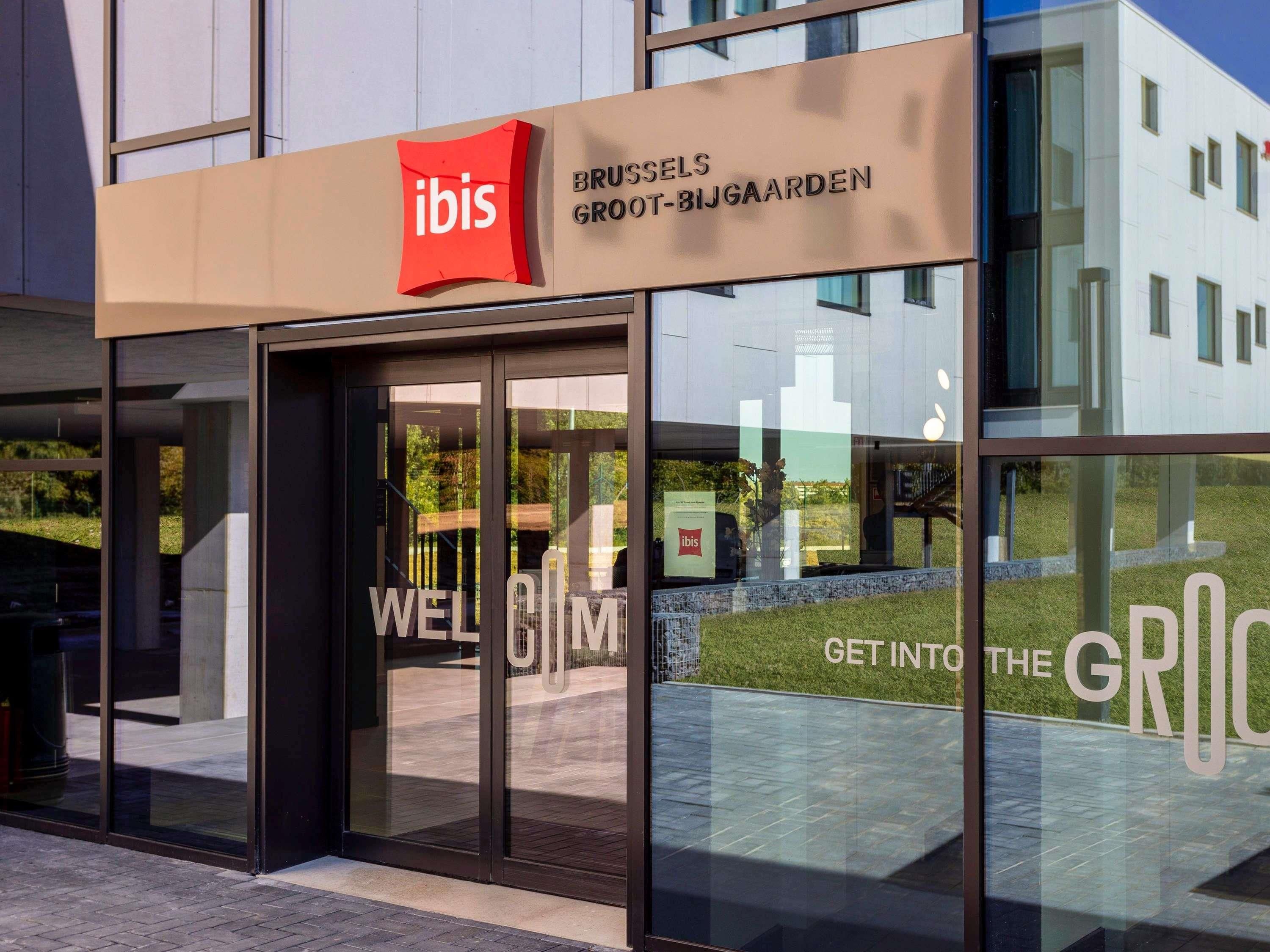 A modern building with a glass facade and a sign reading 'IBIS BRUSSELS GROOT-BIJGAARDEN.'