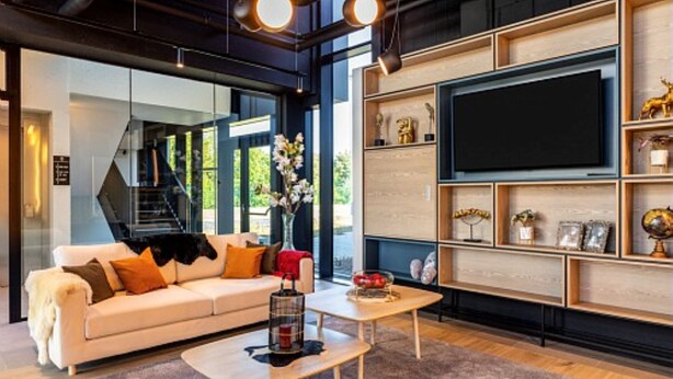 Una sala de estar moderna con un sofá, una mesa de centro y un televisor montado en una pared de madera.