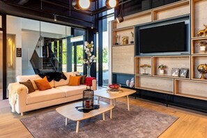A modern living room with a sofa, coffee table, and a TV mounted on a wooden wall.