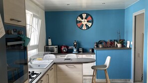 Une cuisine moderne avec un mur d’accent bleu, un îlot central doté de sièges et une horloge.