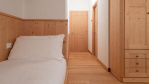 A bedroom with a wooden bed, a wardrobe, and a door leading to another room. - Adda 10 (Valdidentro)