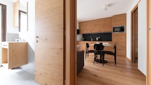 A modern kitchen with wooden cabinets, a black countertop, and a dining area with a round table and chairs.