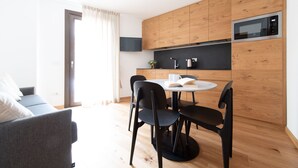 A modern kitchen with wooden cabinets, a microwave, and a round dining table with black chairs.