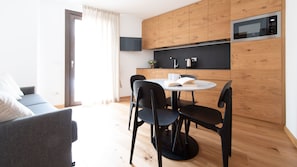 A modern kitchen with wooden cabinets, a microwave, and a round dining table with black chairs.