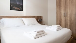 A neatly made bed with white linens and towels, a wooden headboard, and a nightstand with a lamp. - Ciuk 11 (Valdisotto)
