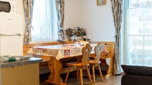 Un comedor con una mesa de madera, sillas y un jarrón de flores.