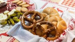 Une table avec des bretzels, du fromage et des cornichons.