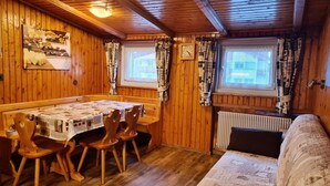 Un intérieur en bois comprenant une table à manger, des chaises, un canapé et une fenêtre avec des rideaux.