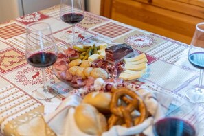 Tábua de frios com diversos embutidos, queijos e biscoitos sobre uma mesa com toalha estampada.