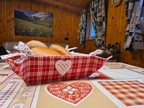 A wooden interior with a checkered tablecloth, a basket of bread, and a heart-patterned table runner. - Your alpine home with panoramic views (Pera)