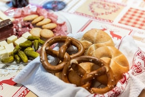Une table sur laquelle on trouve divers aliments, notamment des bretzels, du pain, du fromage et des cornichons.