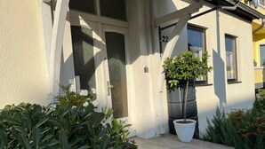 A building with a white facade, a door with a number '22', and a potted plant on the steps.
