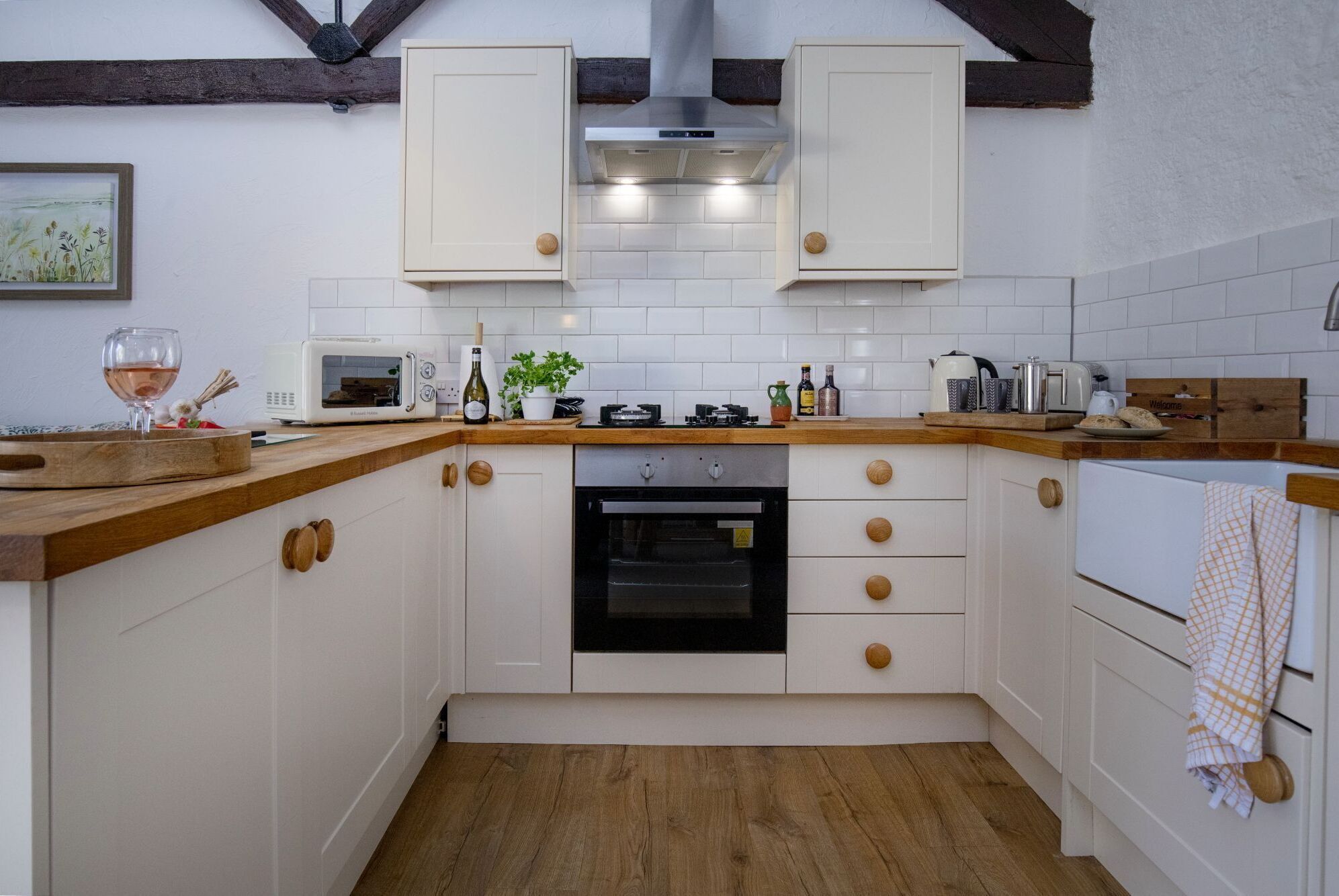 A kitchen with white cabinets, a wooden countertop, a built-in oven, and a microwave.