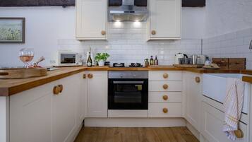 A kitchen with white cabinets, a wooden countertop, a built-in oven, and a microwave.