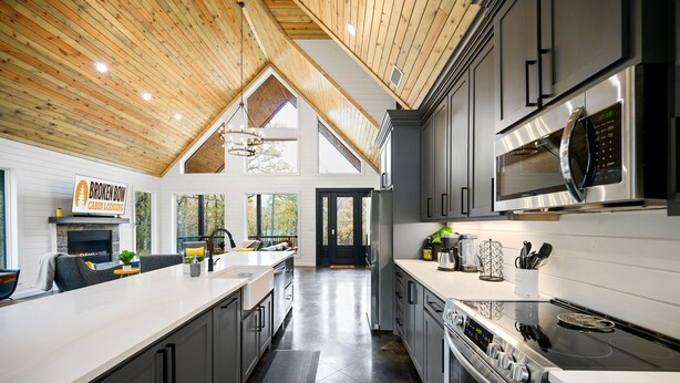 Una cucina moderna con un'isola grande, elettrodomestici in acciaio inossidabile e un soffitto alto con travi in legno.
