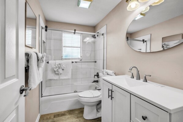 A modern bathroom with a shower, toilet, and sink.