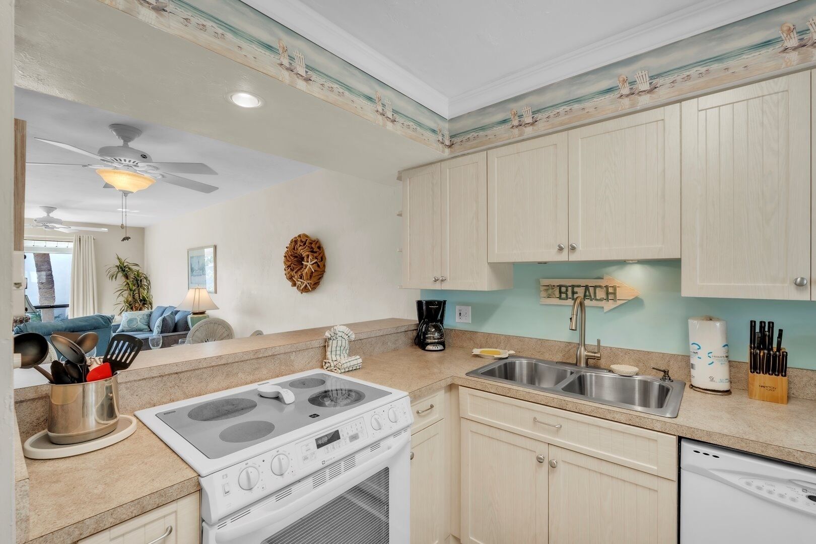 A kitchen with a gas stove, double sink, and light-colored cabinets.