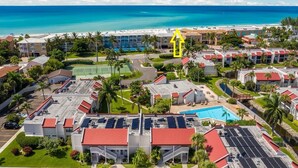 A resort with multiple buildings, a swimming pool, and a beach view.