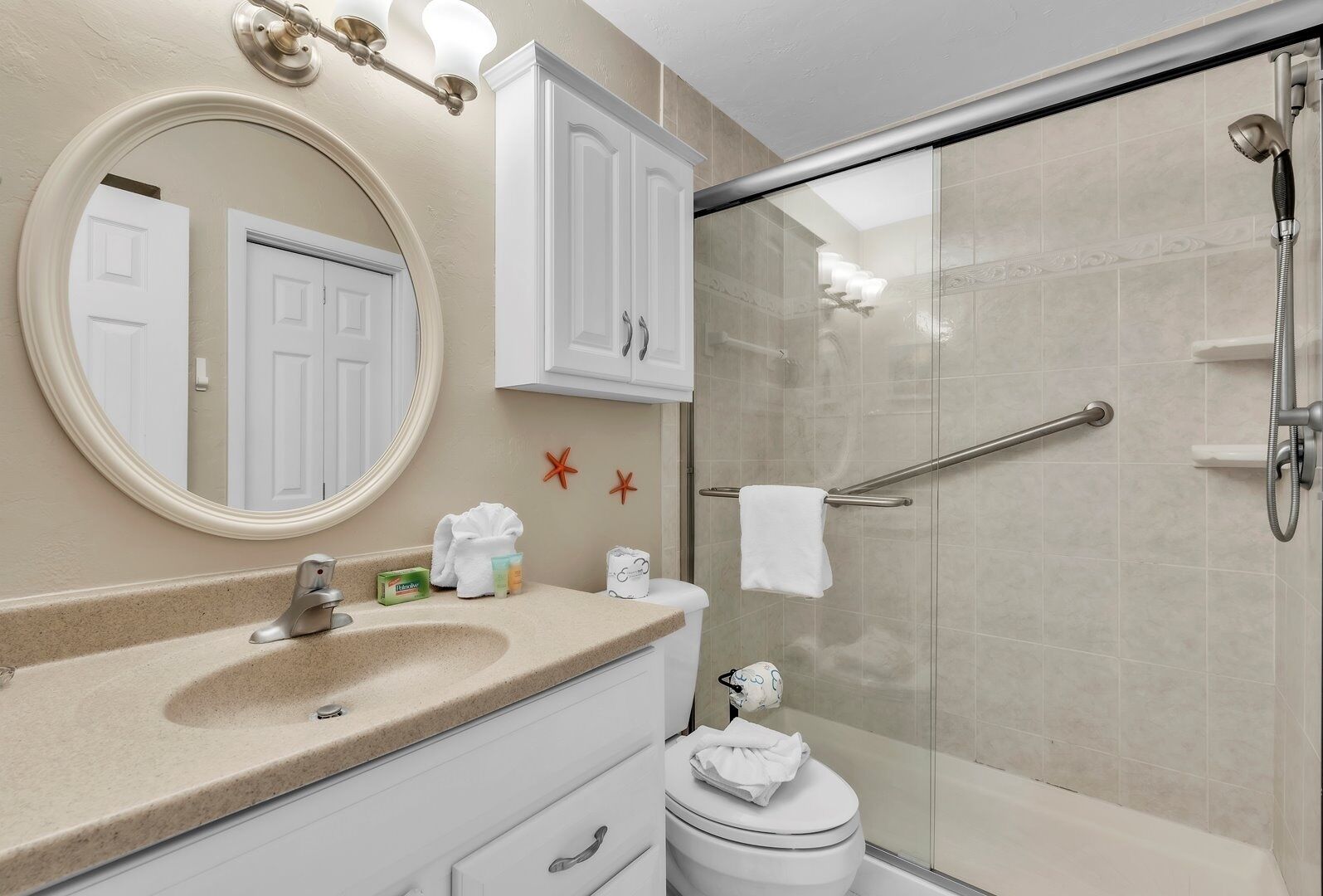 Une salle de bain avec un miroir rond, un lavabo, des toilettes et un espace douche.