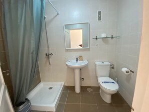 A bathroom with a shower, sink, toilet, and a glass shelf. - Las Lomas (Pajara)