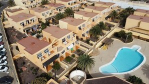 Un ensemble résidentiel comprenant plusieurs immeubles de deux étages, une piscine et un petit espace de stationnement.