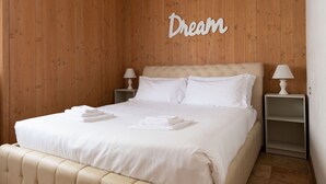 Un dormitorio con una cama, dos mesitas de noche, un radiador y una pared con la palabra 'Dream' escrita.