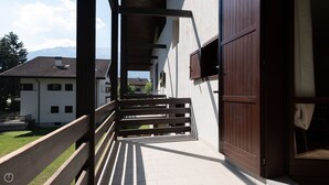Un espacio al aire libre cubierto con un banco de madera, una escalera y vistas a casas y montañas al fondo.