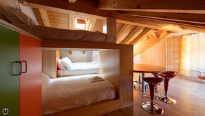 A cozy attic bedroom with a bunk bed, a dining table with chairs, and a red bowl on the floor. - Milano 38 - Carcentina (Bormio)