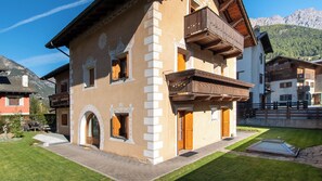 A traditional chalet with a balcony, a stone facade, and a mountain backdrop. - Funivie 6A (Bormio)