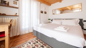 A neatly arranged bedroom with a bed, a chair, a desk, and a mirror. - Sertorelli 60 (Bormio)