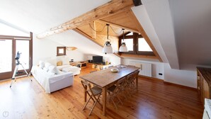A cozy loft bedroom with a wooden ceiling, a white sofa, a dining table, and a telescope. - Sertorelli 60 (Bormio)