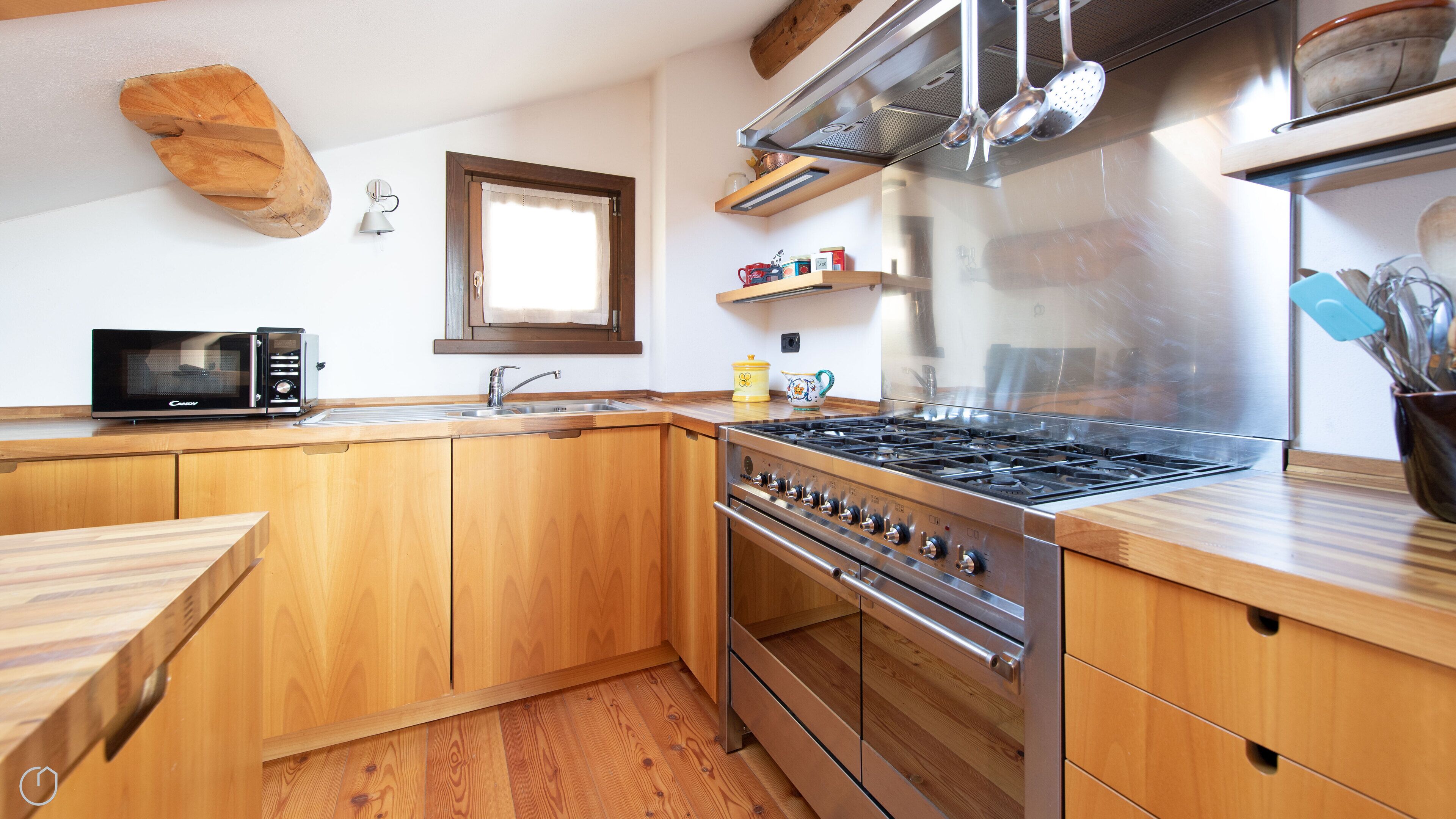 Une cuisine moderne avec des meubles en bois, une cuisinière en acier inoxydable, un four à micro-ondes et un évier.