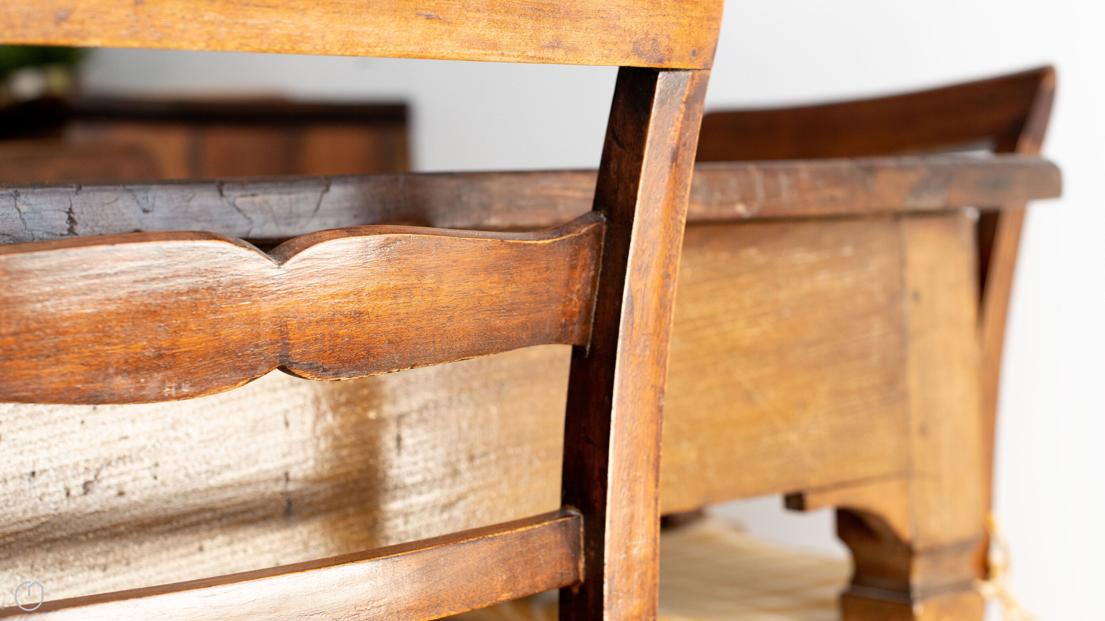 A close-up of a wooden chair with a curved backrest and a wooden table leg.
