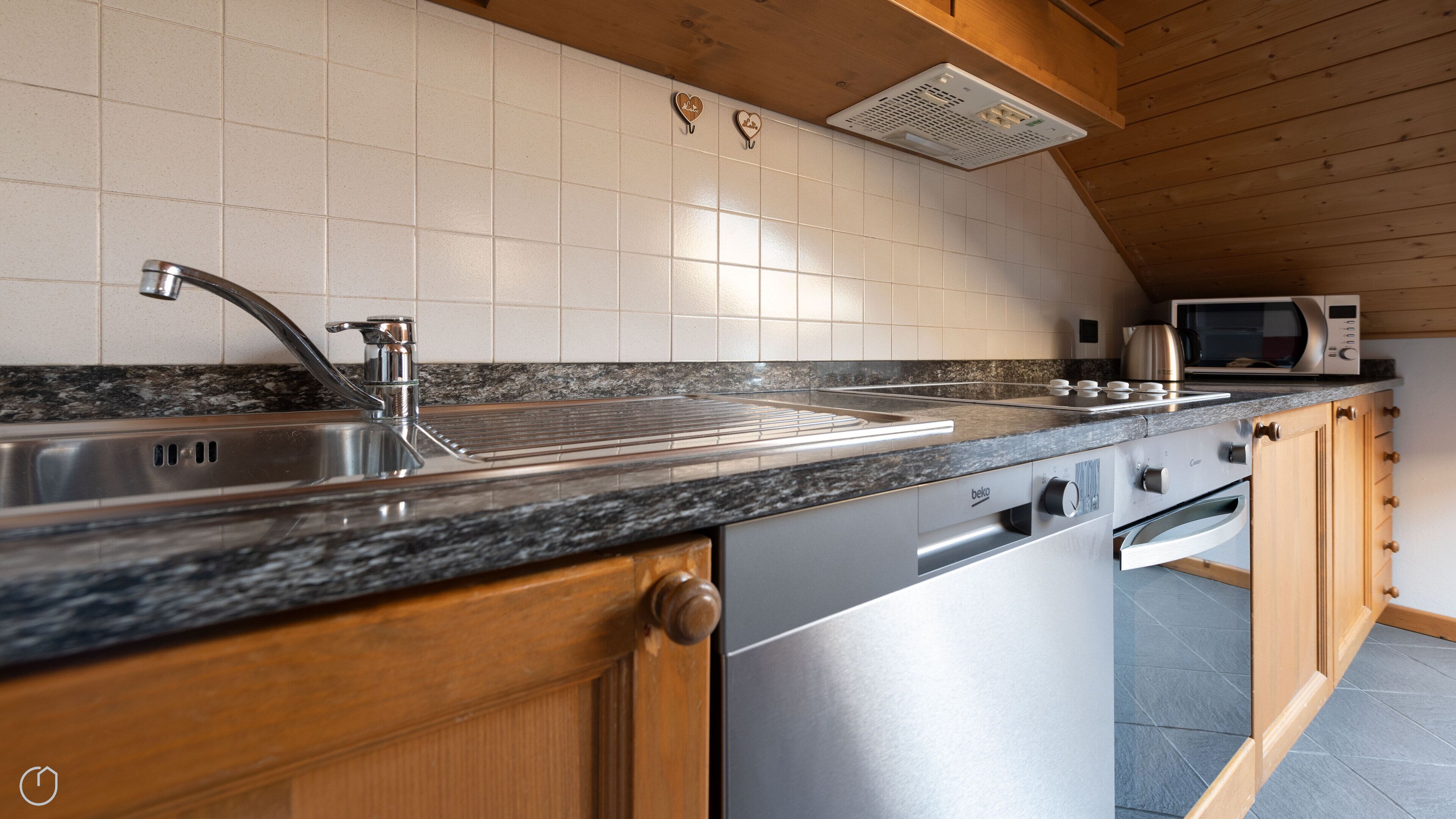 A kitchen with a stainless steel sink, a microwave, and wooden cabinets.