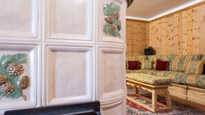 A room with a wooden panel wall, a patterned sofa, a small table, and a decorative door with pinecone designs.