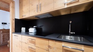 A kitchen with wooden cabinets, a black countertop, a stainless steel sink, and a toaster.