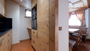 A compact kitchen with wooden cabinets, a black oven, and a window.