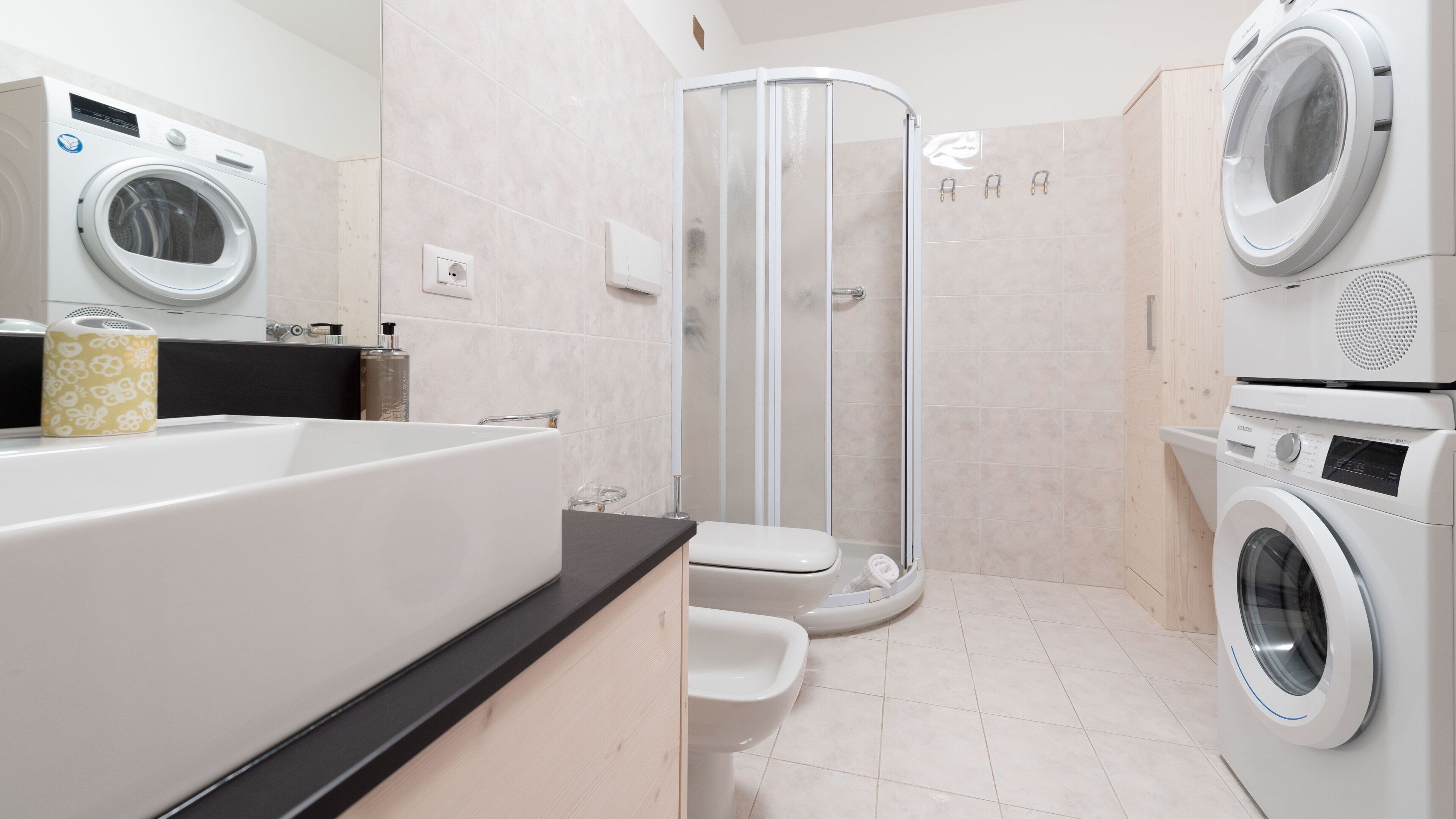 Ein modernes Badezimmer mit Badewanne, Dusche und zwei Waschmaschinen mit Frontlader.