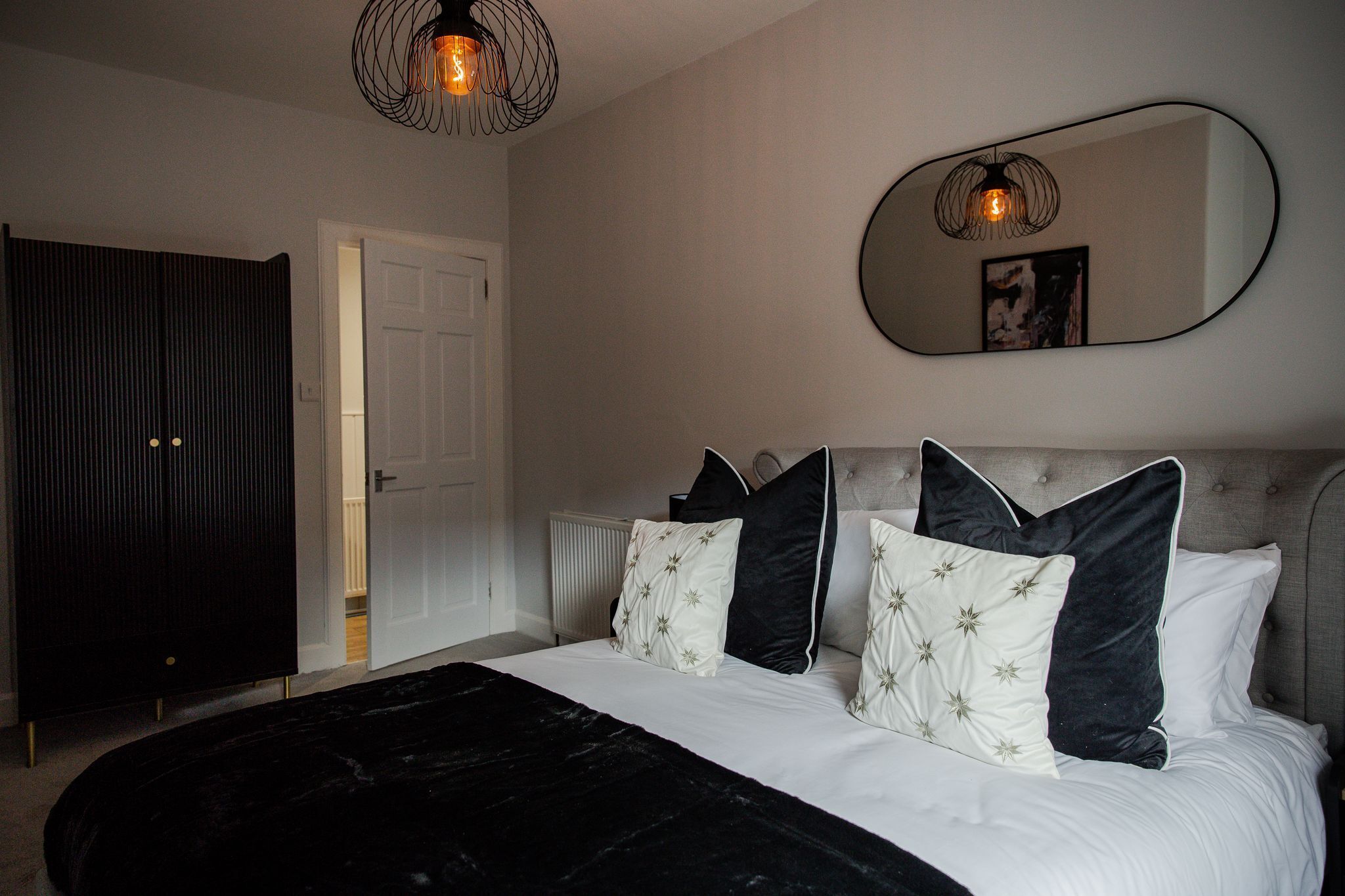 Une chambre à coucher avec un lit, un grand miroir et une armoire.
